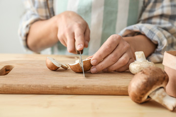 Woman cutting raw mushrooms on wooden board