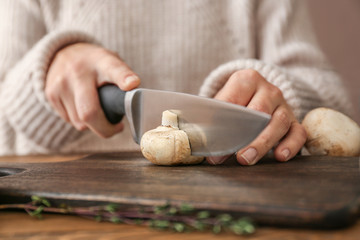 Woman cutting raw mushrooms on wooden board