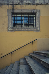 Rome, Italy, window with metal bars along a stone stairway and yellow wall