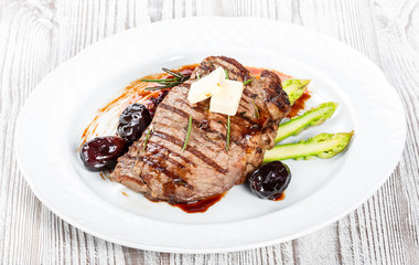 Grilled pork chop steak with dates in honey, rosemary, asparagus and beet salad on wooden background. Hot Meat Dishes. Top view, flat lay