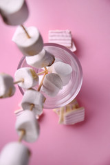 Glass with sweet marshmallows on color table