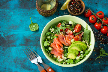Diet menu, Vegan food. Healthy salad with quinoa, arugula, Tomatoes, Salmon and Avocado on blue concrete or stone table. Top view flat lay background. Copy space.