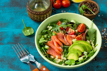 Diet menu, Vegan food. Healthy salad with quinoa, arugula, Tomatoes, Salmon and Avocado on blue concrete or stone table. Copy space.