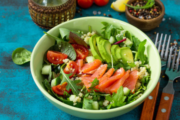 Diet menu, Vegan food. Healthy salad with quinoa, arugula, Tomatoes, Salmon and Avocado on blue concrete or stone table.