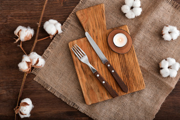 Obraz na płótnie Canvas Cutlery, wooden board and candle with cotton flowers on table