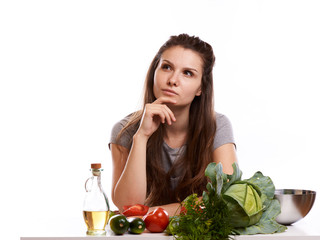 happy adult woman with various fresh vegetables on kitchen table looking at camera