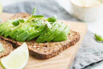 Toast with avocado on a wooden board on a breakfast table. The concept of vegetarian and healthy diet food.