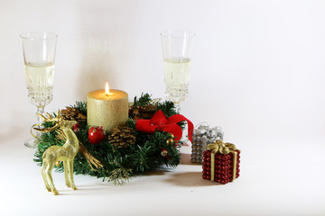 Two glasses of champagne, a golden candle, a wreath on a white background.