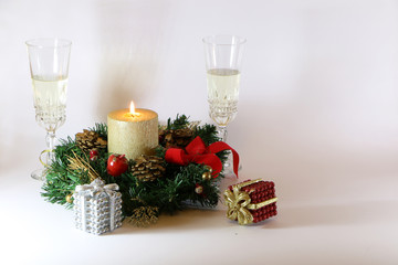 Two glasses of champagne, a golden candle, a wreath on a white background.