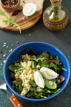 Diet menu, Vegan food. Healthy salad with quinoa, green beans, eggs and salad dressing on a dark stone table.