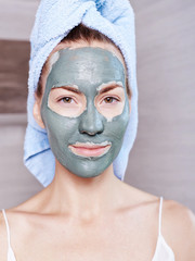 Woman applying mask moisturizing skin cream on face looking in bathroom mirror. Girl taking care of her complexion layering moisturizer. Skincare spa treatment.