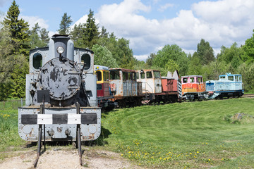 Old train and locomotive. Railroad tracks stretches and green grass and trees. Railway road environment background.