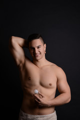 Young man with deodorant on dark background