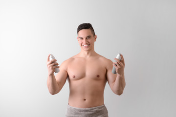 Fototapeta premium Young man with deodorants on light background
