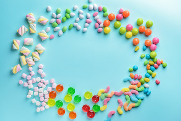 Frame made of tasty sweets on color background