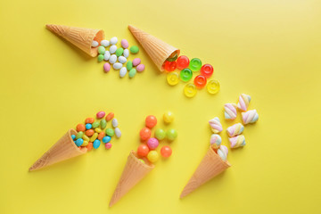 Composition with tasty sweets and waffle cones on color background