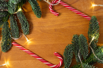 Christmas candys and christmas tree branches with a garland in the wooden background