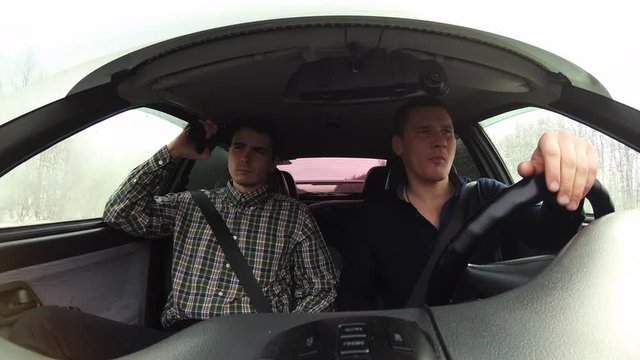A driver carries a passenger who has a gun in his hands. The video's inside the car.