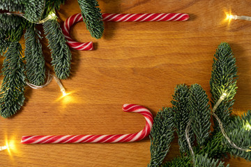 Christmas candys and christmas tree branches with a garland in the wooden background