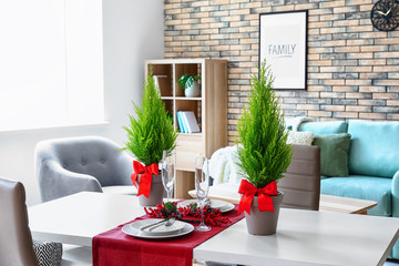 Pots with lemon cypress trees on table set for festive dinner