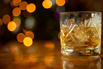 Glass of whiskey bourbon in a crystal glass up close shot Christmas lights background