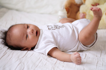 Asian cute baby newborn smile and happy, good mood, on the bed with milk bottle and Teddy bear