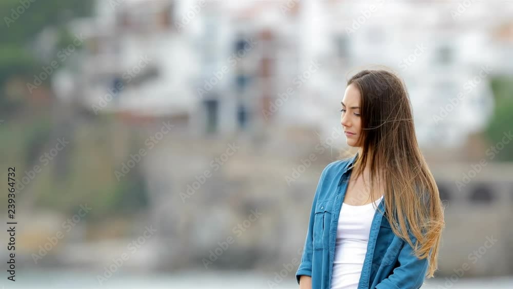 Wall mural Melancholic woman looking away outdoors in a coast town