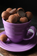 Cup with sweet truffles on table