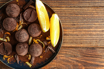 Plate with sweet truffles on wooden table
