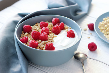 Healthy Breakfast yogurt with granola and raspberry on white wooden background top view