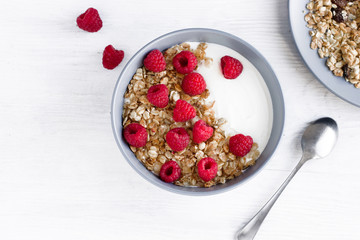 Healthy Breakfast yogurt with granola and raspberry on white wooden background top view