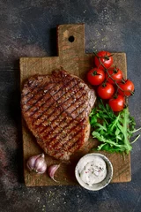 Foto auf Acrylglas Roasted organic rancho beef steak with vegetables and garlic sauce on a wooden cutting board.Top view with copy space. © lilechka75