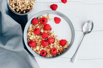 Healthy Breakfast yogurt with granola and raspberry on white wooden background top view