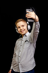 the boy listens to music with headphones and holding a mobile phone,