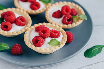 Tartlets with cream and raspberry on a grey plate