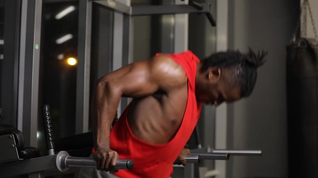 African american man push ups in gym on parallel bars