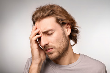 Young man suffering from headache on light background