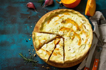 Classic Quiche Lorraine Pie with Pumpkin and Feta Cheese on blue concrete or stone table. Top view flat lay background. Copy space.
