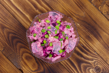 Tasty salad with herring, beetroot, eggs, onion and mayonnaise on wooden table. Top view