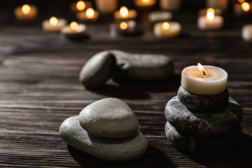 Fototapeta na wymiar Spa stones and burning candle on wooden table