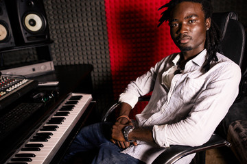 African male sound engineer at work sitting at the mixing console looking at the camera