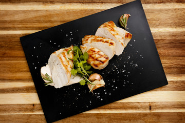 Plan view of seasoned succulent roasted chicken breast, with garlic and rosemary garnish