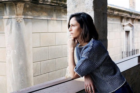 Junge Frau steht auf Balkon in modernem Haus mit Blick auf Altstadt