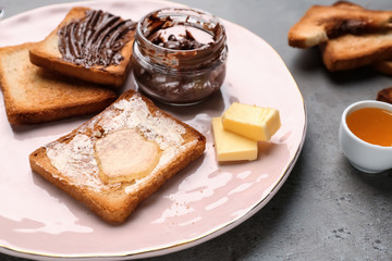 Plate with tasty toasts and chocolate spreading on table, closeup