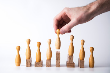 Hand selecting a wooden figure. Business leadership concept