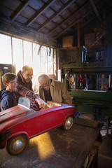 Obraz na płótnie Canvas Multi generation family in aDIY workshop to repair a pedal car