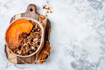 Fall breakfast bowl with cinnamon granola, coconut yogurt, chia seeds and pumpkin puree. Healthy...