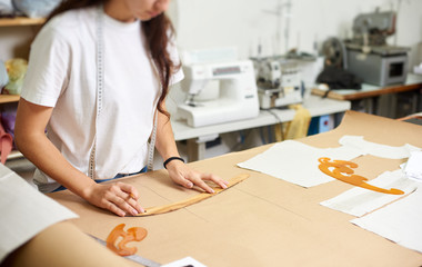 Working place in design studio. Young female designer drawing flat paper patterns using measuring...