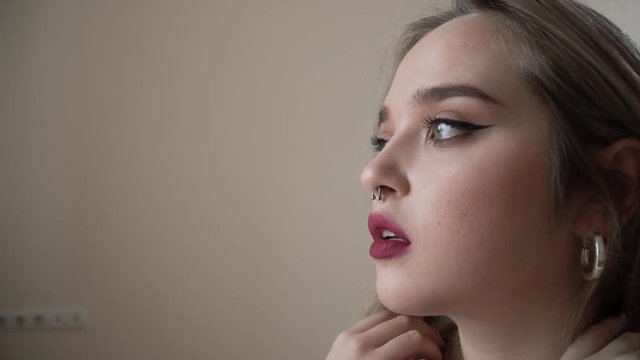 Portrait of glamour girl with piercing nose looking in the distance close up. Young woman with piercing nose is sad and thinkful.