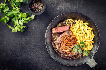 Traditional dry aged sliced roast beef with fried onion rings and Swabian spaetzle as top view in a...